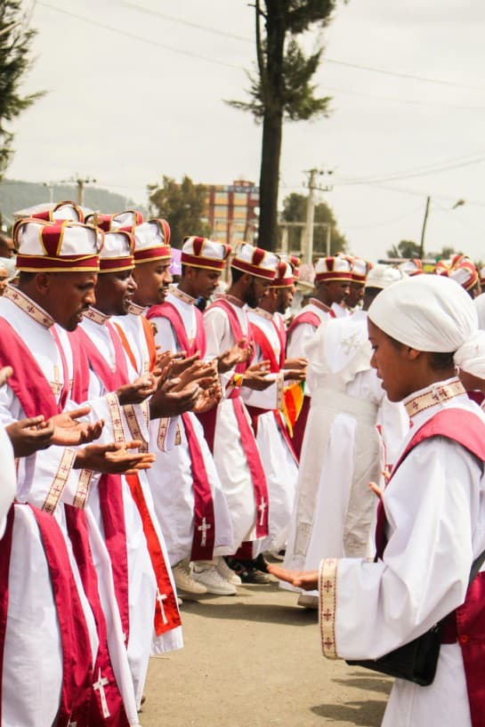 Group of Ethiopian Christians celebrating Easter in traditional white and red robes, participating in a religious ceremony outdoors