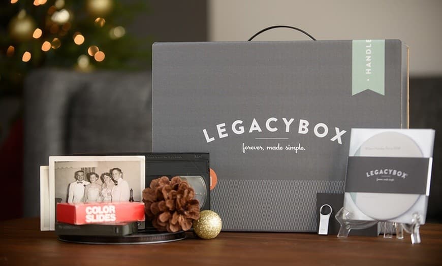 A Legacybox kit displayed with various old family photos, color slides, and a USB drive, illustrating a service that helps preserve and digitize cherished memories for long-term safekeeping.