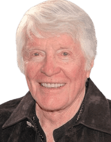 A warm, close-up portrait of an elderly man with white hair, smiling brightly. He is dressed in a casual dark jacket, exuding a friendly and lively demeanor. The outdoor setting with soft, blurred greenery in the background adds a relaxed and approachable atmosphere to the image.