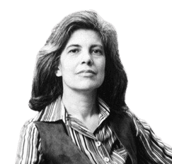 A black-and-white portrait of a confident woman with voluminous hair, wearing a striped shirt and a vest, sitting in front of a bookshelf filled with books. The image captures a scholarly and intellectual atmosphere, emphasizing her poised demeanor and thoughtful expression.