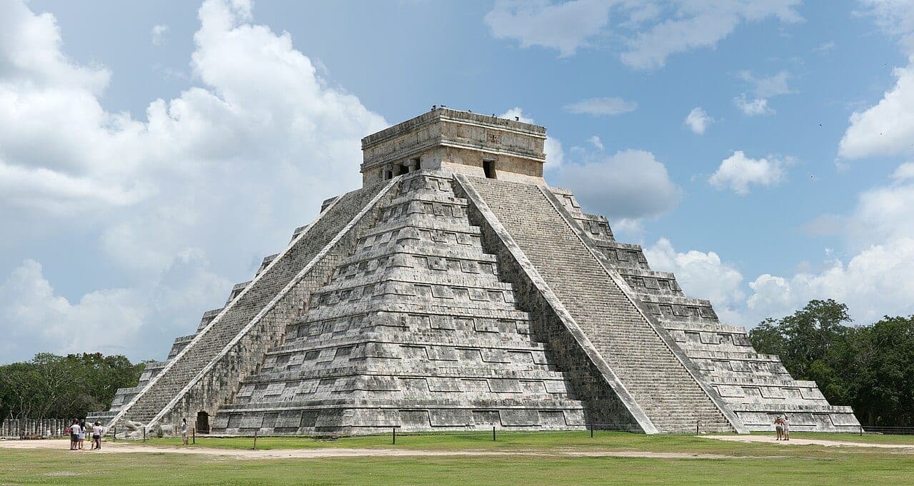 El Castillo, the terraced step-pyramid at the heart of Chichen Itza, rising above the grass plaza under a clear sky